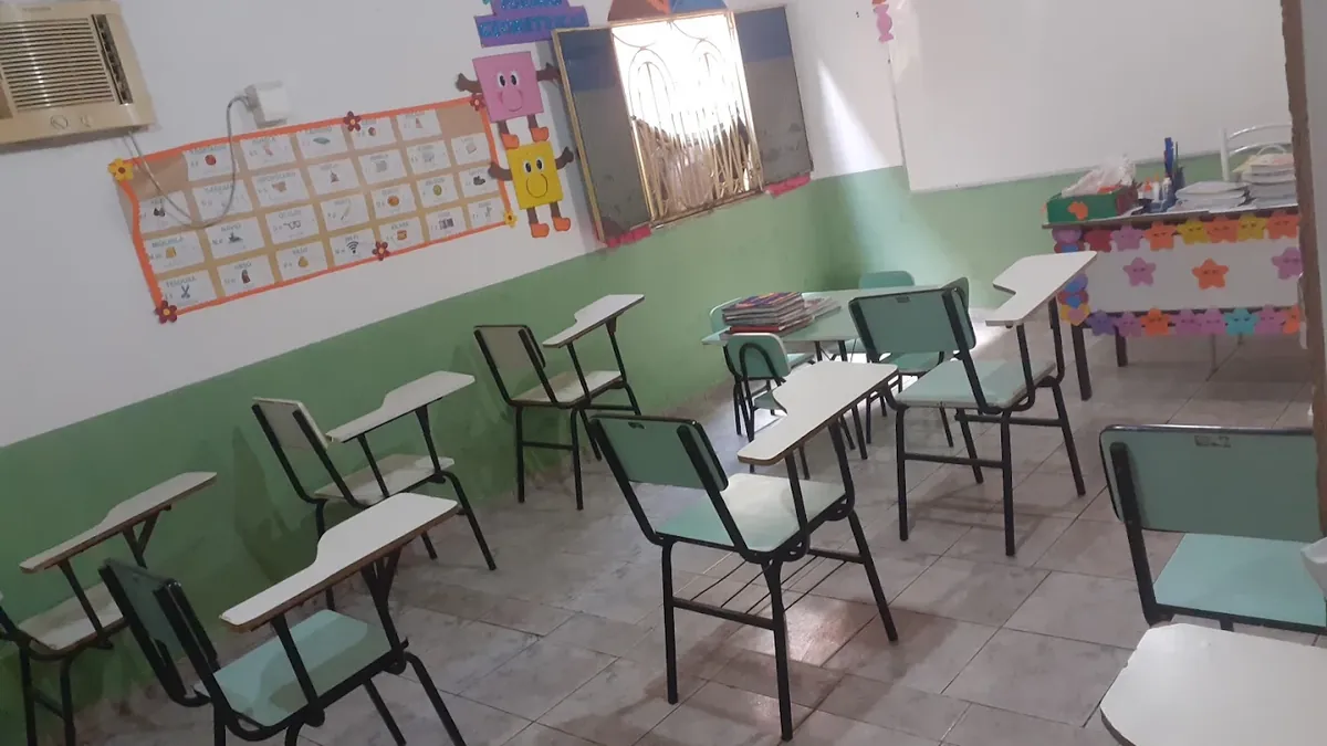 Sala de aula do Pequenos Criadores com carteiras organizadas, ar-condicionado na parede e painel de alfabetização ilustrado.